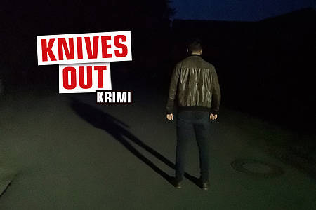 Mann auf dunkler Straße mit Aufschrift "Knives Out"