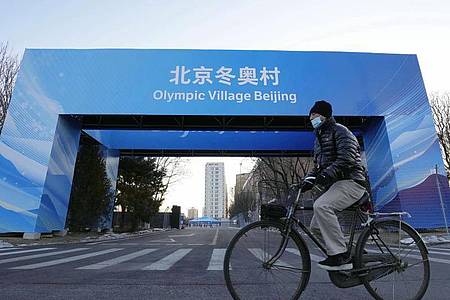 Ein Mann fährt in der Nähe des Athletendorfs in der chinesischen Hauptstadt Peking Fahrrad. Foto: -/Kyodo/dpa