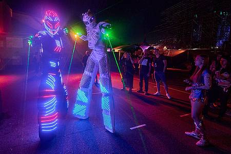 Stelzenläufer mit leuchtenden Kostümen  beim Technofestival «Nature One» im Hunsrück.