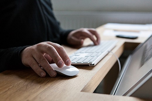 Eine Person die eine Computertastertur mit Maus bedient